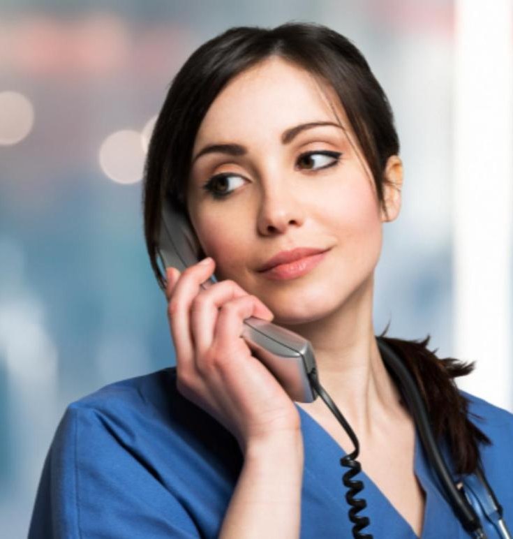 A nurse in scrubs answers a phone call