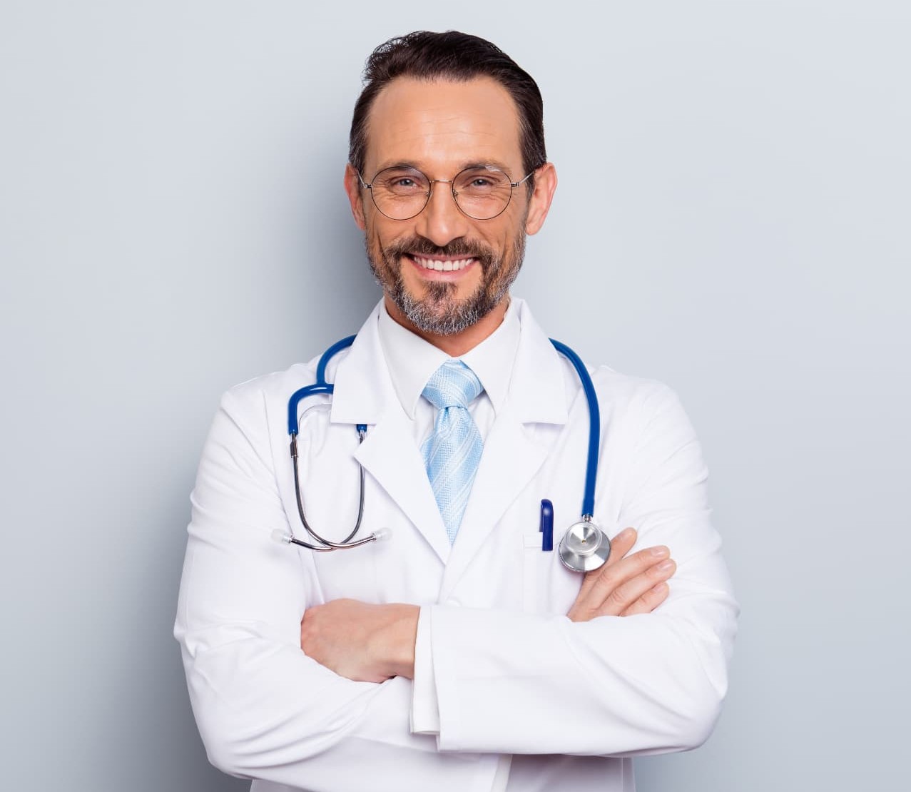 A smiling physician in a white coat and glasses with a stethoscope