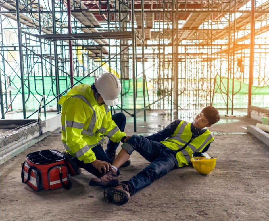 A safety officer gives first aid to an injured construction worker